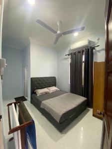 een slaapkamer met een bed en een plafondventilator bij Tok Mek Homestay in Setiu