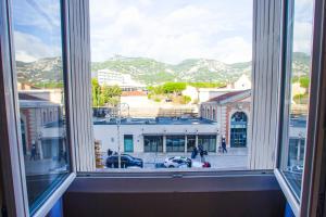 a window with a view of a city with mountains at Le Cosy Studio - 60m gare - Hypercentre - Clim - Wifi in Toulon