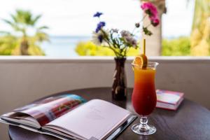 a drink and a book on a table with a book at Levantino Studios & Apartments in Vasilikos +45 photos