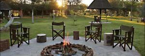 a group of chairs and a fire pit in a yard at Fiume Lodge CC in Groutfontein