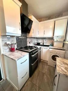 a kitchen with white cabinets and a stove top oven at Lovely 2 bedroom with driveway close to Quayside in Sheriff Hill