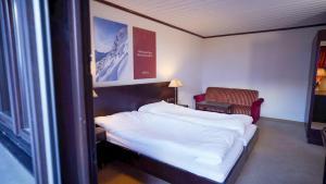 a hotel room with a bed and a chair at Hotel Rosanna by Alpeffect Hotels in Sankt Anton am Arlberg