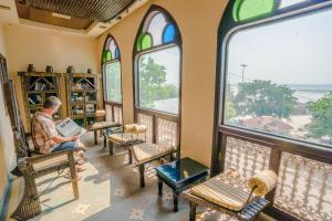 a man sitting in a chair in a room with windows at Palace On Ganges - Heritage Hotel in Varanasi