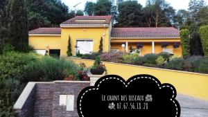 a yellow house with a sign in front of it at Le chant des oiseaux - Au pied de la voie cyclable in Crévéchamps