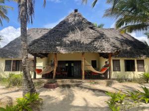 une maison avec des hamacs et un toit de chaume dans l'établissement Embedodo Beach House, Ushongo beach, Pangani, à Ushongo Mabaoni