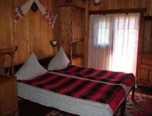 a bedroom with a bed with a red and black blanket at Villa Doina in Voronet
