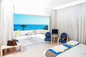 a bedroom with a bed and a balcony with the ocean at Vrissiana Boutique Beach Hotel in Protaras