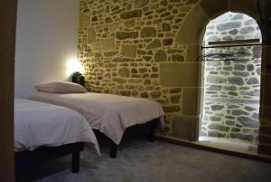 2 letti in una camera con parete in pietra di Le Duclos, appartement rez-de-jardin Dinan centre a Dinan