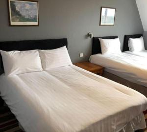 Habitación de hotel con 2 camas con sábanas blancas en The Airman Hotel, en Shefford