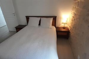 ein Schlafzimmer mit einem weißen Bett mit einer Lampe in der Unterkunft Le Gîte de la fontaine in Neuvy-le-Roi