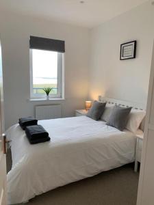 1 cama blanca en un dormitorio con ventana en Sea View Penthouse Marina Apartment, en Portishead