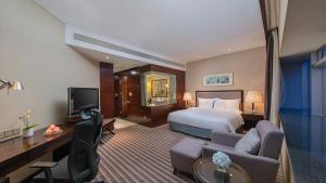 a hotel room with a bed and a couch and a tv at Binbei Yiho Hotel in Xiamen