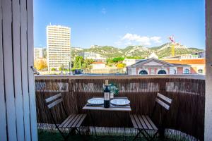 a table with a bottle of wine and two chairs on a balcony at La Clé T2 Love Room Balnéo, Clim, Proche Gare in Toulon
