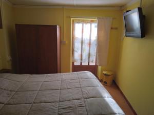 a bedroom with a bed and a television on the wall at B&B LA MARMOTTA in Coazze