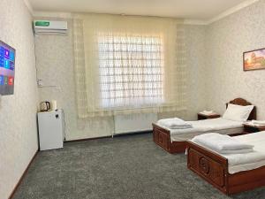 Habitación hospitalaria con 2 camas y ventana en CHO'PON OTA Hotel, en Samarkand