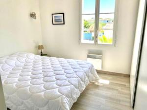 um quarto branco com uma grande cama branca e uma janela em Villa piscine a La Flotte en Re em La Flotte