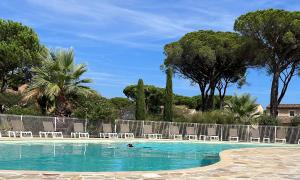 eine Person, die in einem Pool mit Stühlen und Bäumen schwimmt in der Unterkunft Villa Varelle in Gassin