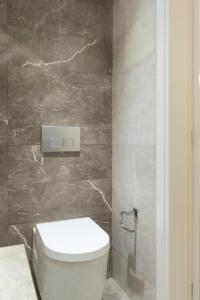 a bathroom with a white toilet and a stone wall at Voda Luxury Residence #101 in Athens