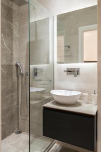 La salle de bains est pourvue d'un lavabo et d'une douche en verre. dans l'établissement Voda Luxury Residence #101, à Athènes