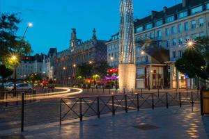 een stadsstraat 's nachts met een hoge toren bij Résidence Adam à part in Valenciennes