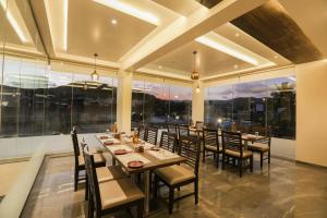 a dining room with tables and chairs and large windows at Enrise by Sayaji, Khed Shivapur Pune in Pune