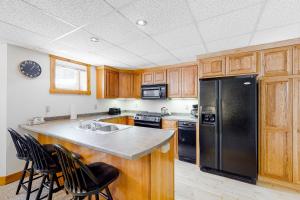 a kitchen with wooden cabinets and a black refrigerator at Jay Peak Village Home 367B in Jay