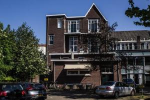 een bakstenen gebouw met auto's geparkeerd voor het bij ROOTS Tiny House in Tilburg