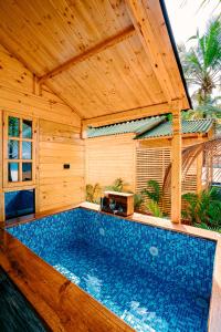 an outdoor swimming pool with a wooden pergola at orange sky beach bungalow in Agonda