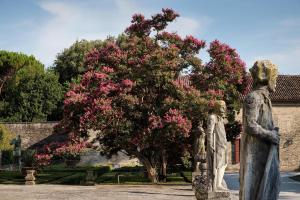 duas estátuas em frente a uma árvore com flores cor-de-rosa em Castello di Roncade em Roncade