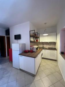 a kitchen with white cabinets and a white refrigerator at Trilocale climatizzato con cortile in San Teodoro