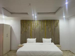 1 dormitorio con 1 cama blanca grande con almohadas blancas en White Gold Hotel, en Ikeja