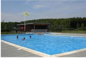 a group of people in a large swimming pool at Big Family villa 12p big garden with bathtub and jacuzzi in Zeewolde