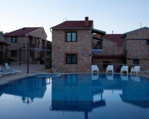 a swimming pool with white chairs in front of a building at Lithea Mountain Resort in Florina