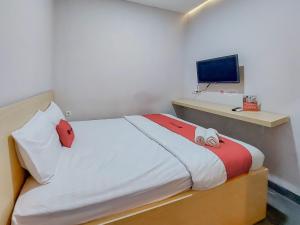 a bedroom with a bed with a tv on a wall at Reddoorz at Cempaka Guesthouse Tarakan in Sibengkok