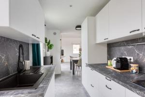 a kitchen with white cabinets and black counter tops at Premium Flat 6 People with billard and Terrace Stade de France in Saint-Denis