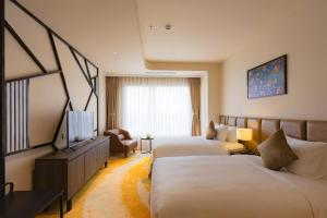 una camera d'albergo con due letti e una televisione di La Vela Hue Hotel a Hue