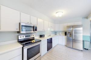 uma cozinha com armários brancos e electrodomésticos de aço inoxidável em Dewey Villas --- 24 Dickinson Ave, Unit #8B em Dewey Beach