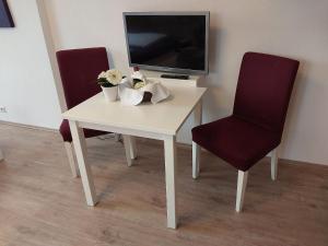 uma mesa branca com duas cadeiras e uma televisão em The Cozy Lindau No 3 em Lindau