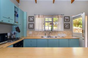 a kitchen with blue cabinets and a sink and a window at Tweni Cottage in Clovelly
