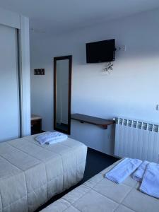 two beds in a room with a tv on the wall at Hostal La Pinilla in Segovia