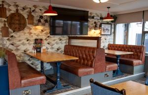 a restaurant with brown leather booths and tables at The Bay Horse Hotel in Haydock