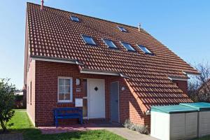una casa de ladrillo rojo con un banco azul delante de ella en Nordseemuschel, en Norddeich