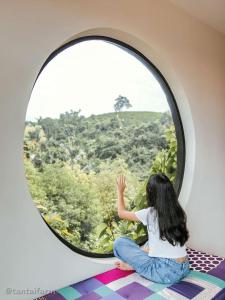 a young girl looking out of a round window at Tantai Eco Farm Stay At Khao Yai in Ban Sap Noi