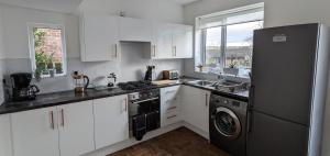 a kitchen with white cabinets and a black refrigerator at Durham & University On Your Doorstep (Free Parking) in Durham