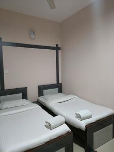 two twin beds in a room with white walls at Hotel Satyam in Jaigaon