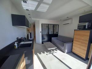 eine Küche und ein Wohnzimmer mit einem Sofa und einem Waschbecken in der Unterkunft CAP'NOMAD Studio Côté Mer - balcon - piscine - parking in Cap d'Agde