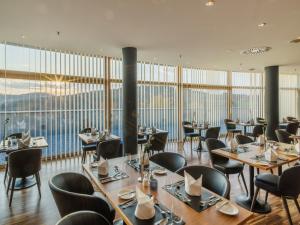 um restaurante com mesas e cadeiras e janelas grandes em Falkensteiner Balance Resort Stegersbach - Adults only em Stegersbach