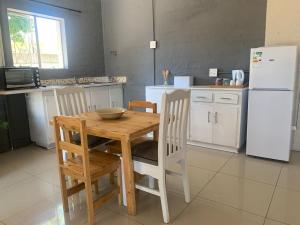 een keuken met een houten tafel en een witte koelkast bij Framesby Guesthouse in Port Elizabeth