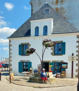 a woman sitting on a bench in front of a building at L'appartementducroisic - Sur le port, vue mer in Le Croisic