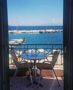 d'une table et de chaises sur un balcon avec vue sur l'eau. dans l'établissement Myrto, à Tyros